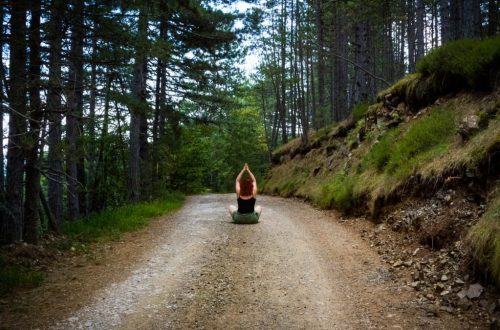 A person meditating on a forest path, embracing nature's tranquility in summer.